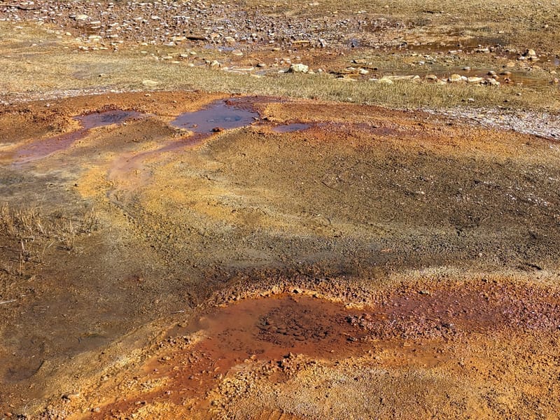 Mineral-crusted, rust-red puddles